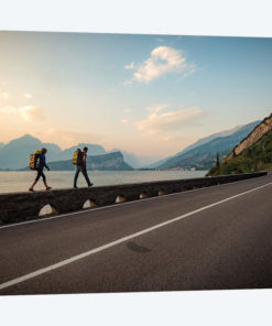 Two Climbers Walk Home Next To A Road And Lago di Gardo, Arco, Trentino, Italy