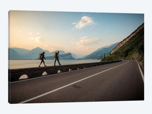 Two Climbers Walk Home Next To A Road And Lago di Gardo, Arco, Trentino, Italy
